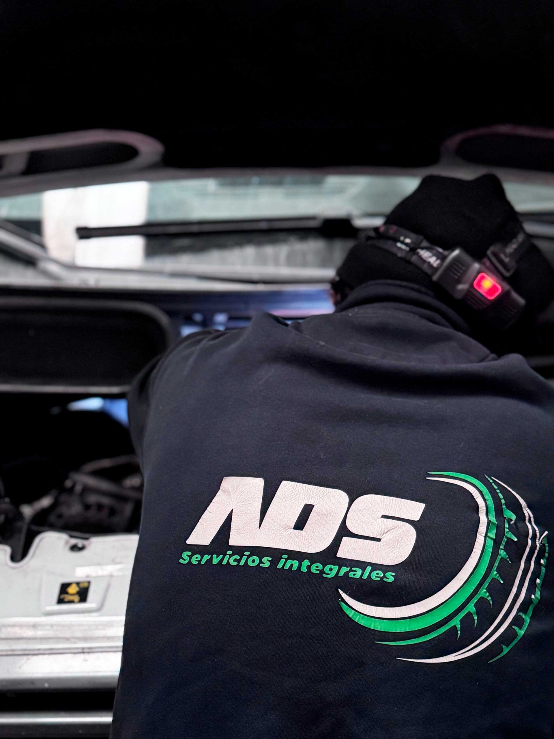 Técnico de ADS Servicios Integrales con uniforme del taller realizando reparación y mantenimiento de vehículo en Noblejas, Toledo.